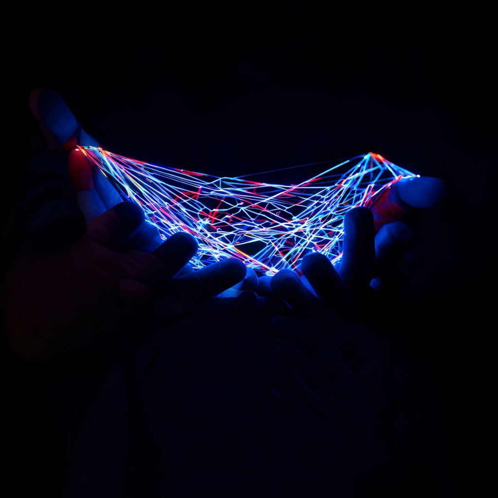 a picture of a hand surrounded in darkness holding multi colored lines symbolizing network connections